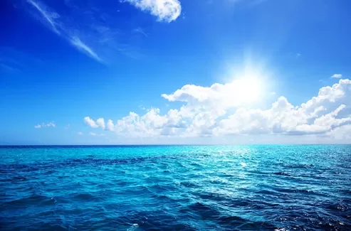 عکس استوک دریای آبی و آسمان ابری و خورشید